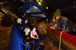 Visitors in a time car coming face to face with Vikings on a longboat.